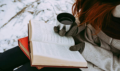 image of girl reading in the snow with a cup of tea